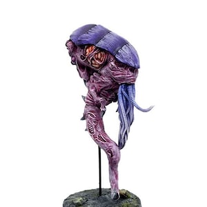 May include: A purple and pink painted miniature of a creature with a long, thin body and multiple tentacles. The creature is standing on a black base with a grey and green textured surface.