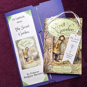May include: A copy of "The Secret Garden" by Frances Hodgson Burnett, with a matching lapbook. The book cover shows a girl in a yellow coat. A white tag with a key illustration is attached. The lapbook is purple and white.