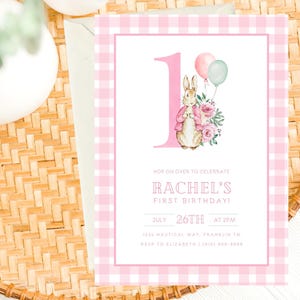 May include: Pink and white gingham patterned invitation with a watercolor illustration of a bunny rabbit holding a bouquet of flowers. The invitation says "Hop on over to celebrate Rachel's First Birthday!" with the date and time of the party.