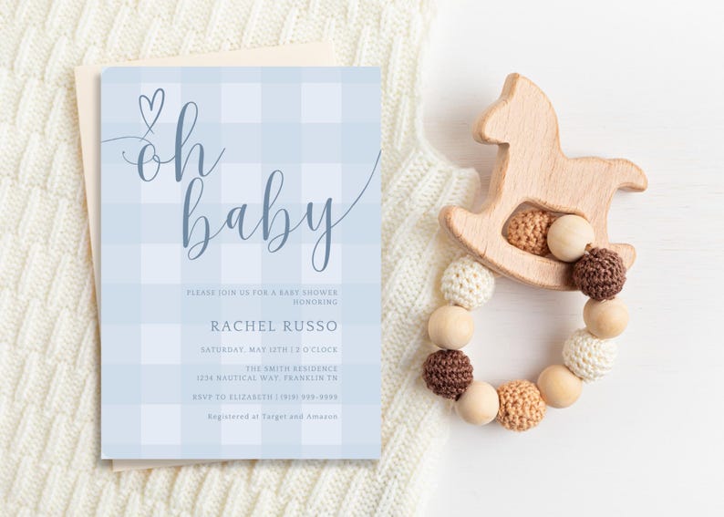Puede incluir: Una invitaci&oacute;n a una baby shower en papel gingham azul y blanco con el texto "oh baby" en letra cursiva. La invitaci&oacute;n incluye el nombre Rachel Russo, la fecha y la hora de la ducha, y la direcci&oacute;n.