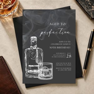May include: A dark grey birthday invitation card featuring a white line drawing of a liquor bottle and a glass with ice cubes. The text reads AGED TO perfection, JOIN US TO CELEBRATE JOHN'S 50TH BIRTHDAY, SATURDAY JULY 28, 1234 NAUTICAL WAY, FRANKLIN TN 37000.
