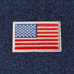 May include: A white embroidered patch of the American flag on a blue denim background.
