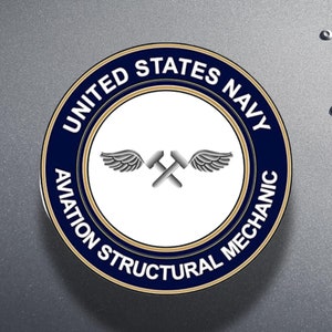 May include: A blue and gold round badge with the text "UNITED STATES NAVY AVIATION STRUCTURAL MECHANIC". The badge features a pair of crossed hammers with wings.