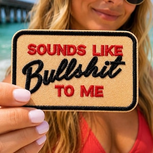 May include: A rectangular embroidered patch with a tan background and a black border. The text reads "SOUNDS LIKE" in red, "Bullshit" in black script, and "TO ME" in red. The patch features a durable stitched edge finish.