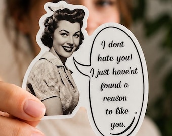 Può includere: Un adesivo fustellato con un'illustrazione in bianco e nero di una donna sorridente con una camicia a colletto. Un fumetto sul lato destro contiene il testo nero: I dont hate you! I just havent found a reason to like you.