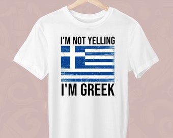 Peut inclure: T-shirt blanc avec l'inscription "I'M NOT YELLING I'M GREEK" en noir. Le t-shirt présente un drapeau grec vieilli bleu et blanc, avec une croix et des rayures.