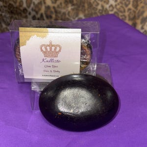 May include: Two black soap bars in clear plastic packaging. The packaging has a white label with a gold crown and the text "Kallisto Glow Bar Face & Body".