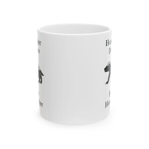 May include: White ceramic mug featuring a black and white illustration of a badger. The mug has the words "Honey Badger Don't Care" printed on it in black, with the badger image repeated on both sides. A fun gift for animal lovers.