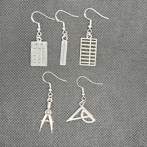 May include: A set of six silver earrings featuring various math-themed charms, including a calculator, ruler, abacus, compass, and protractor.
