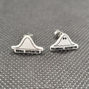 May include: A pair of silver stud earrings with white plastic charms. One charm is a bell curve with the text "NORMAL DISTRIBUTION" and the other charm is a ghost with the text "PARANORMAL DISTRIBUTION".