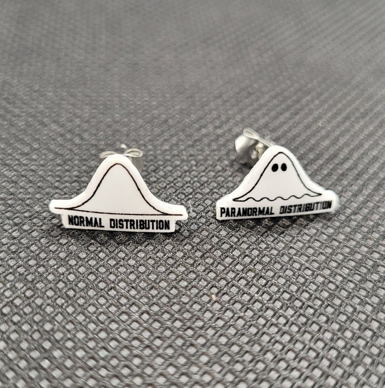 May include: A pair of silver stud earrings with white plastic charms. One charm is a bell curve with the text "NORMAL DISTRIBUTION" and the other charm is a ghost with the text "PARANORMAL DISTRIBUTION".