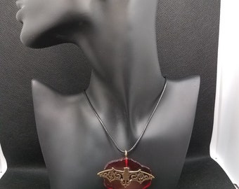 Gothic steampunk bat necklace on blood red background.