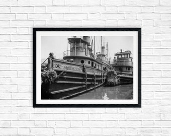 May include: Black and white photograph of two tugboats docked side-by-side. The tugboat in the foreground is named "Bess".