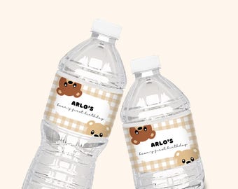 May include: Two clear plastic water bottles with brown and tan labels. The labels have a gingham pattern and feature a cartoon bear and the text "Arlo's Bear's First Birthday".