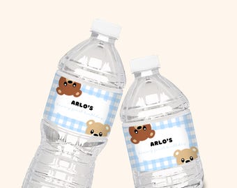 May include: Two clear plastic water bottles with blue and white checkered labels. The labels feature a brown bear cartoon and the text "Arlo's first birthday".