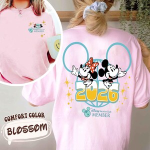 May include: Pale pink Comfort Color t-shirt featuring a Disney Vacation Club design. The front has a small Mickey and Minnie Mouse graphic. The back shows a larger design with Mickey and Minnie, the year 2020, and the Disney Vacation Club logo.