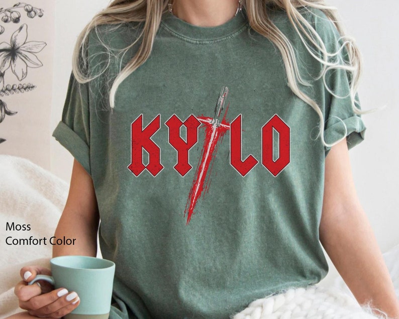 May include: A moss green t-shirt featuring a red graphic of the word "KYLO" in a heavy metal font with a red lightsaber behind it.