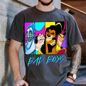 May include: Dark gray t-shirt featuring a colorful graphic of four cartoon villains: Hades, Captain Hook, Scar, and Jafar. The words "BAD BOYS" are printed in a teal and pink font below the characters.