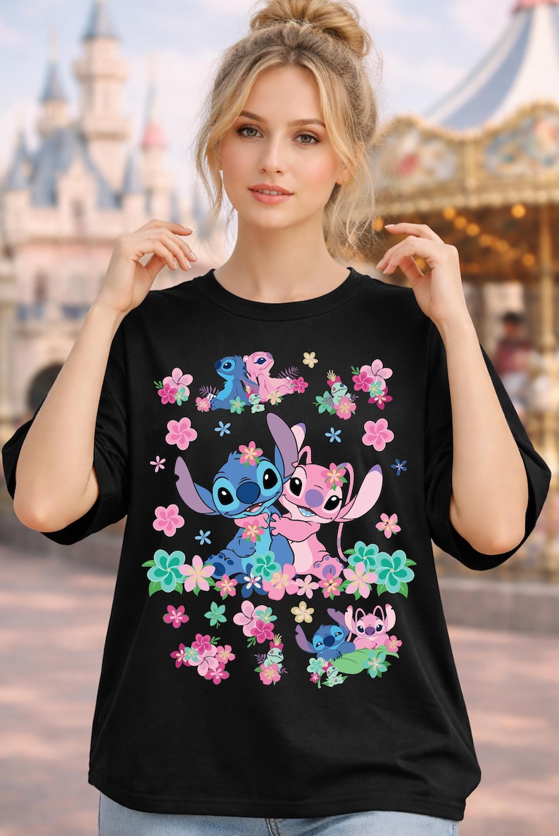 May include: Black t-shirt featuring a colorful graphic of the Disney characters Stitch and Angel surrounded by flowers. The design includes Stitch and Angel in various poses, with pink and blue floral accents.
