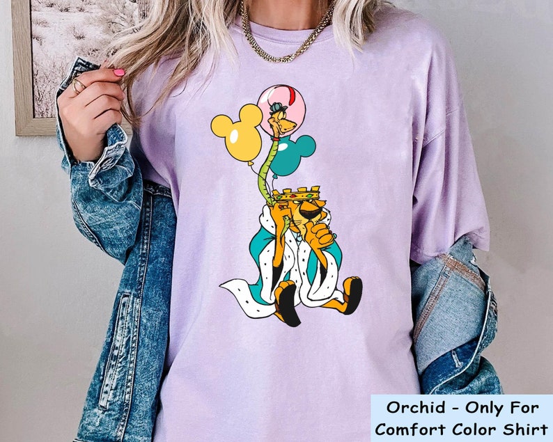 May include: A purple t-shirt with a cartoon image of a king holding balloons. The balloons are yellow, blue, and pink. The text "Orchid - Only For Comfort Color Shirt" is at the bottom of the image.