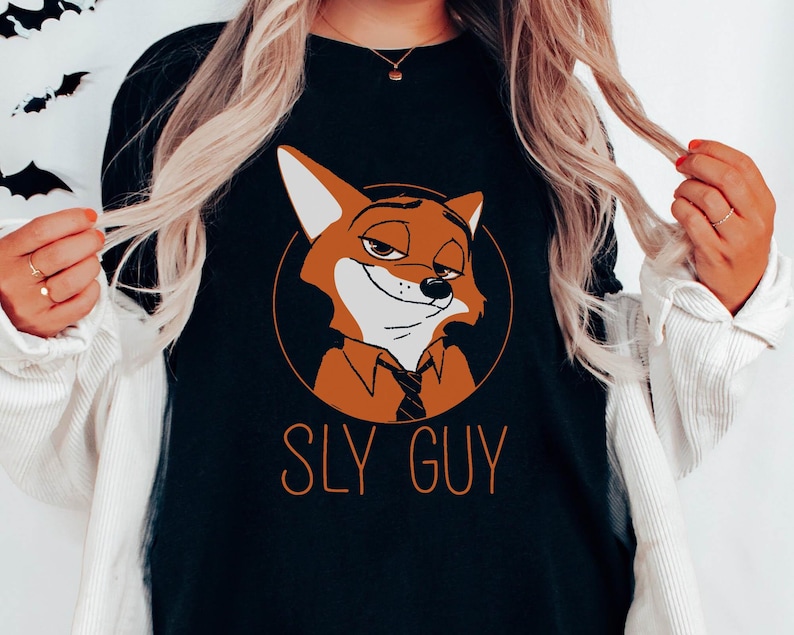May include: Black long-sleeved top with a cartoon fox character in an orange circle. The fox has a sly expression and is wearing a tie. The text "SLY GUY" is printed below the fox in orange.