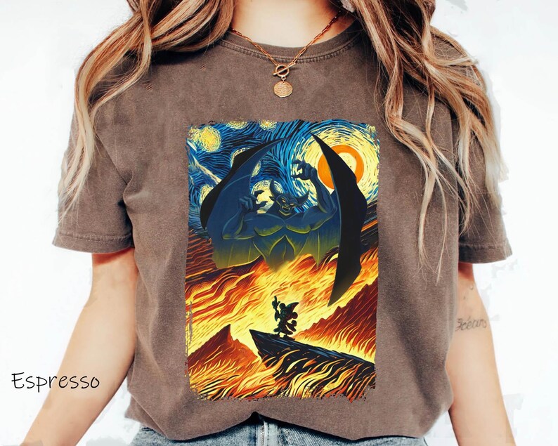 May include: A brown t-shirt with a graphic print of a scene from the Disney movie *The Hunchback of Notre Dame*. The scene depicts the villain, Frollo, in a fiery inferno, with the sky above resembling Vincent van Gogh's *Starry Night* painting.