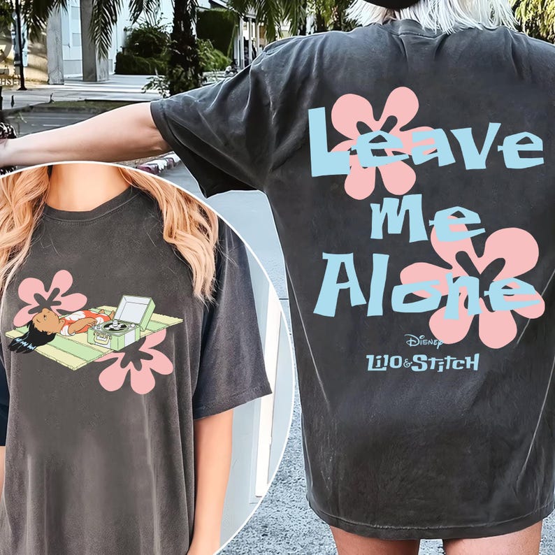 Puede incluir: Camiseta gris oscuro con un dise&ntilde;o de Lilo & Stitch. La parte delantera muestra a Lilo relaj&aacute;ndose con un tocadiscos y flores. La parte trasera tiene el texto "Leave Me Alone" con detalles florales. Logotipo de Disney Lilo & Stitch en la parte inferior.