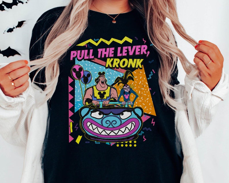 Puede incluir: Camiseta negra con un dise&ntilde;o retro de los 90 con los personajes Kronk e Yzma de la pel&iacute;cula de Disney El Emperador y sus locuras. El texto de la camiseta dice "Pull the Lever, Kronk".