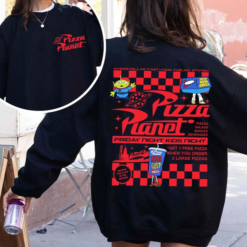 Op de afbeelding: Zwart sweatshirt met een rood-wit geruit patroon en een afbeelding van het Pizza Planet restaurant uit de Toy Story film. De afbeelding bevat de tekst "Pizza Planet", "Interstellar Fast-Food Fueling Station", "Friday Night Kids Night", en "Get 1 Free Pizza When You Order 2 Large Pizzas".