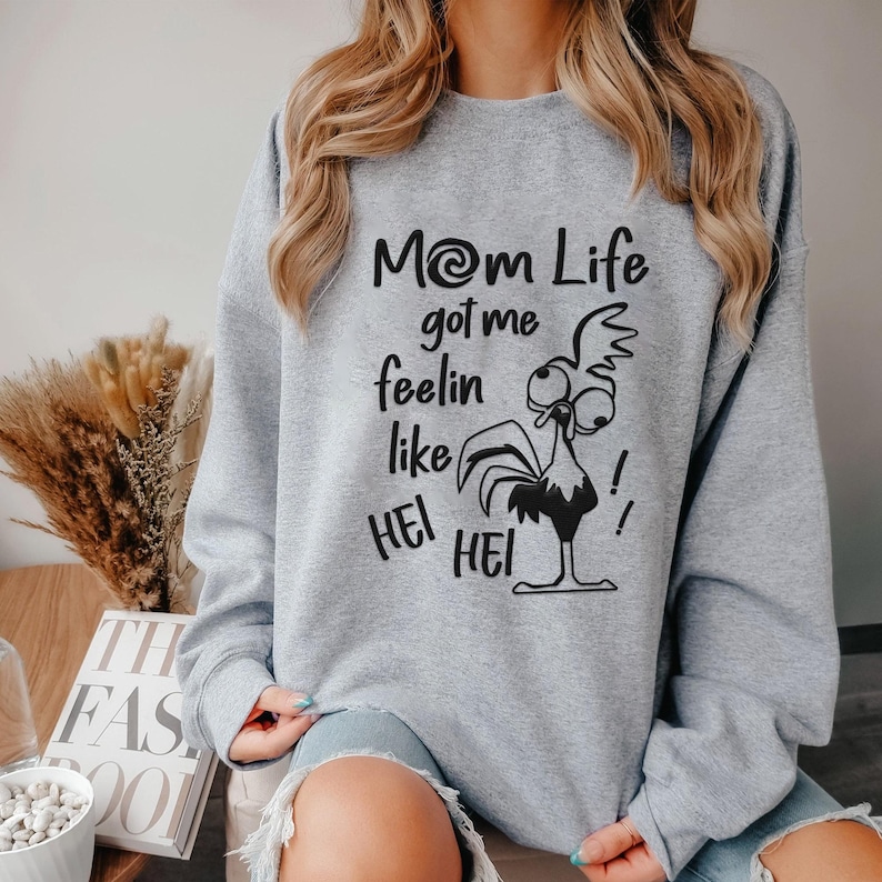 May include: Gray sweatshirt with a black graphic of a cartoon chicken and the text "Mom Life got me feelin like Hei Hei!"