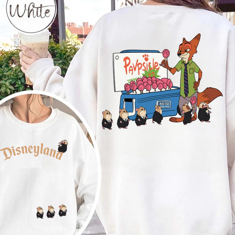 Puede incluir: Sudadera blanca con una ilustraci&oacute;n de dibujos animados de un zorro vendiendo paletas a peque&ntilde;os animales. El texto "Pavpsicle" est&aacute; encima de las paletas. El logotipo de Disneyland est&aacute; en la parte delantera.