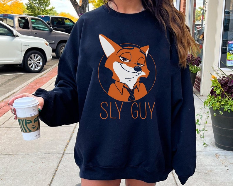May include: Navy blue sweatshirt with an orange cartoon fox wearing a tie, inside a circle. The text "SLY GUY" is printed below the fox in orange. The sweatshirt is a casual style, suitable for everyday wear.