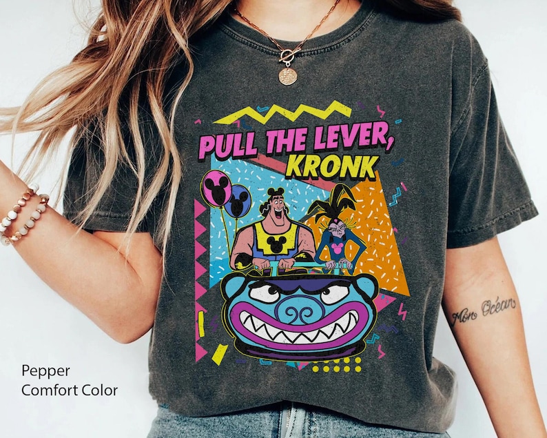 Puede incluir: Una camiseta negra con un gr&aacute;fico de estilo vintage de los 90 que presenta personajes de la serie animada "Las locuras del emperador". El gr&aacute;fico incluye el texto "Pull the Lever, Kronk" y presenta a Kronk, Yzma y Kuzco.