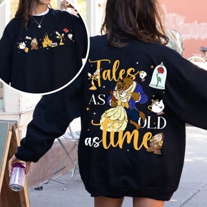 May include: Black sweatshirt featuring a graphic print of Belle and the Beast from Beauty and the Beast. The text "Tales as old as time" is printed in yellow on the sweatshirt.