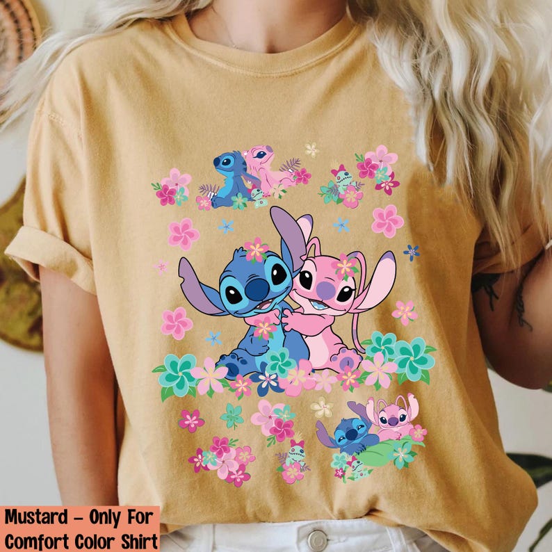 May include: Mustard-colored comfort color shirt featuring a graphic of Stitch and Angel embracing, surrounded by pink and blue flowers. The shirt also has the text "Mustard - Only For Comfort Color Shirt" at the bottom.