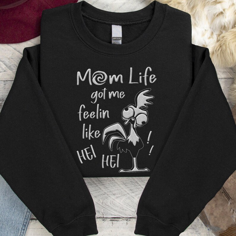 May include: Black sweatshirt with a white embroidered design of a rooster with the text "Mom Life got me feelin like Hei Hei!"