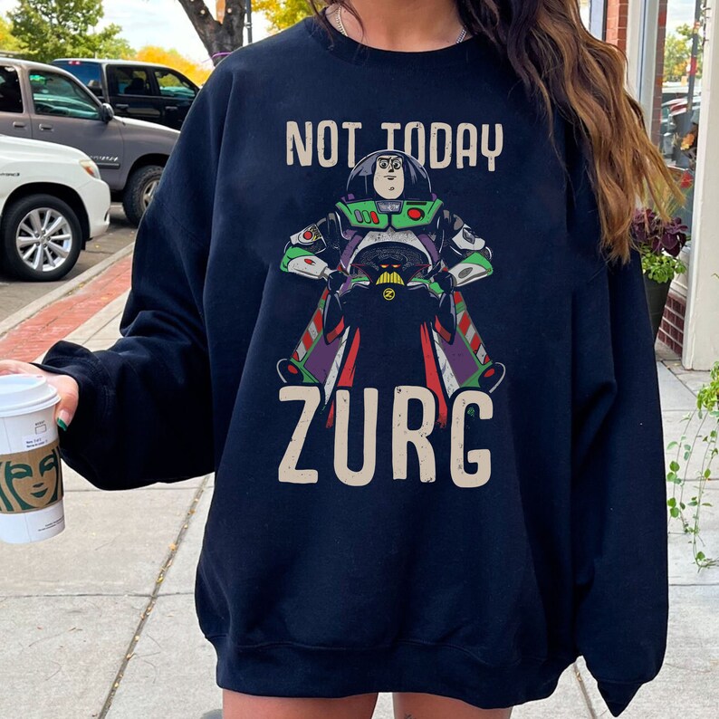 May include: Black sweatshirt with a graphic of Buzz Lightyear from Toy Story, riding a rocket and saying "Not Today Zurg".