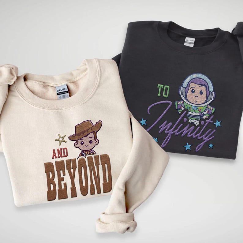 Puede incluir: Dos sudaderas con dise&ntilde;os de personajes de dibujos animados. Una es de color crema con un gr&aacute;fico de vaquero y las palabras "AND BEYOND" en marr&oacute;n. La otra es gris oscuro con un gr&aacute;fico de Buzz Lightyear y las palabras "TO Infinity" en morado.