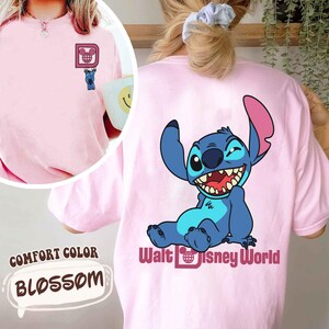 May include: Pink Comfort Colors t-shirt with a small Stitch graphic on the front and a larger Stitch graphic with "Walt Disney World" text on the back. The shirt is a light pink color, with the word "Blossom" in a speech bubble.