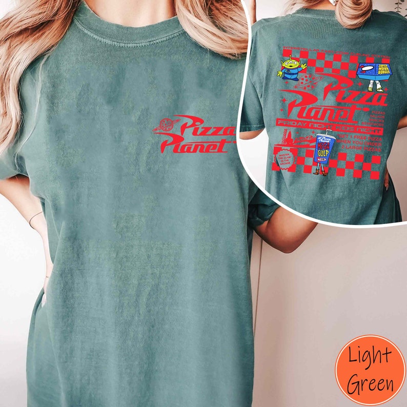 Op de afbeelding: Een lichtgroen T-shirt met een rode afbeelding van het Pizza Planet-logo. De achterkant van het shirt heeft een rood-wit geruit ontwerp met een Pizza Planet-logo, een cartoon-alien en een pizzadoos.