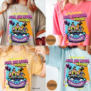 Puede incluir: Cuatro camisetas de diferentes colores con una imagen de dibujos animados de Kronk de la pel&iacute;cula de Disney El Emperador y sus locuras. Las camisetas son de color caqui, sand&iacute;a, mostaza y azul vaquero. La imagen de las camisetas dice "Tira de la palanca, Kronk".