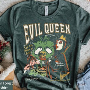 May include: A dark green t-shirt with a vintage-style graphic of the Evil Queen from Snow White. The graphic features the Evil Queen holding a poisoned apple, with the text "Evil Queen", "Go on, have a bite", "Don't be frightened", and "Cast your curse".