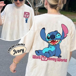 May include: Ivory-colored Comfort Colors t-shirt featuring a cartoon Stitch character on the back, with the words "Walt Disney World" below. The front has a small graphic of Stitch and a Mickey Mouse head.