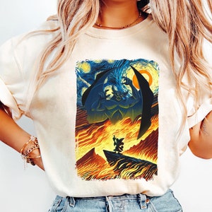 May include: A white t-shirt with a graphic print of a blue and green demon with wings, standing over a fiery landscape. The background is a starry night sky, reminiscent of Vincent van Gogh's 'Starry Night'.