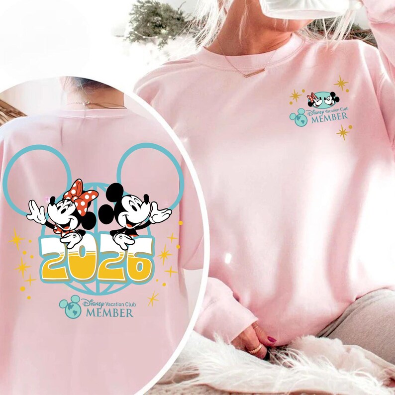 May include: Pale pink sweatshirt with a Mickey and Minnie Mouse design, the text "2026", and "Disney Vacation Club MEMBER". The back features a light blue outline of Mickey Mouse ears.