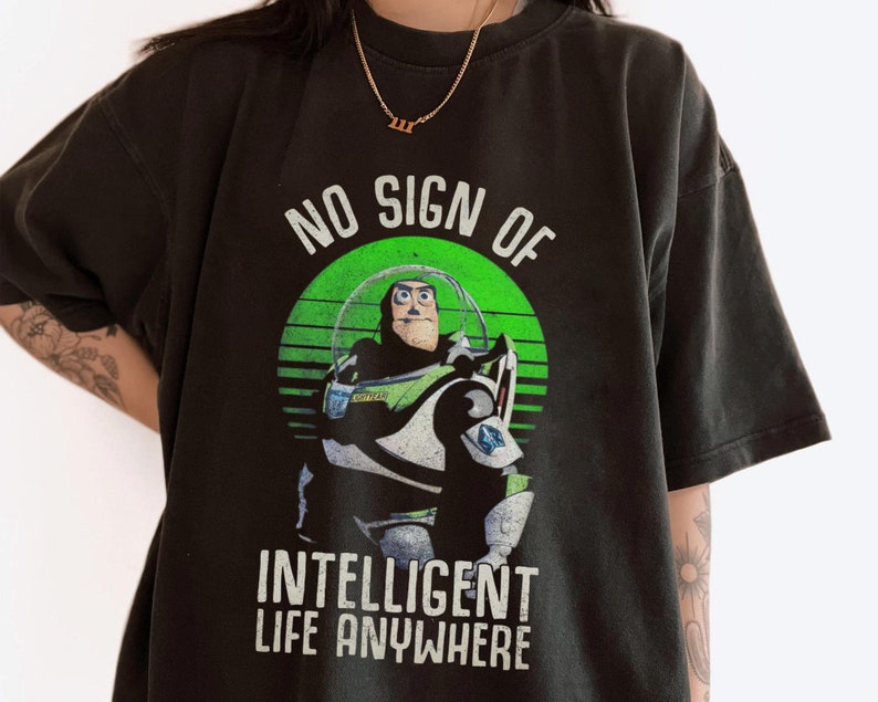 以下が含まれることがあります： トイストーリーの バズ・ライトイヤーが描かれた、緑、白、黒のグラフィックがプリントされた黒いTシャツ。グラフィックには「No Sign of Intelligent Life Anywhere」というテキストが書かれています。