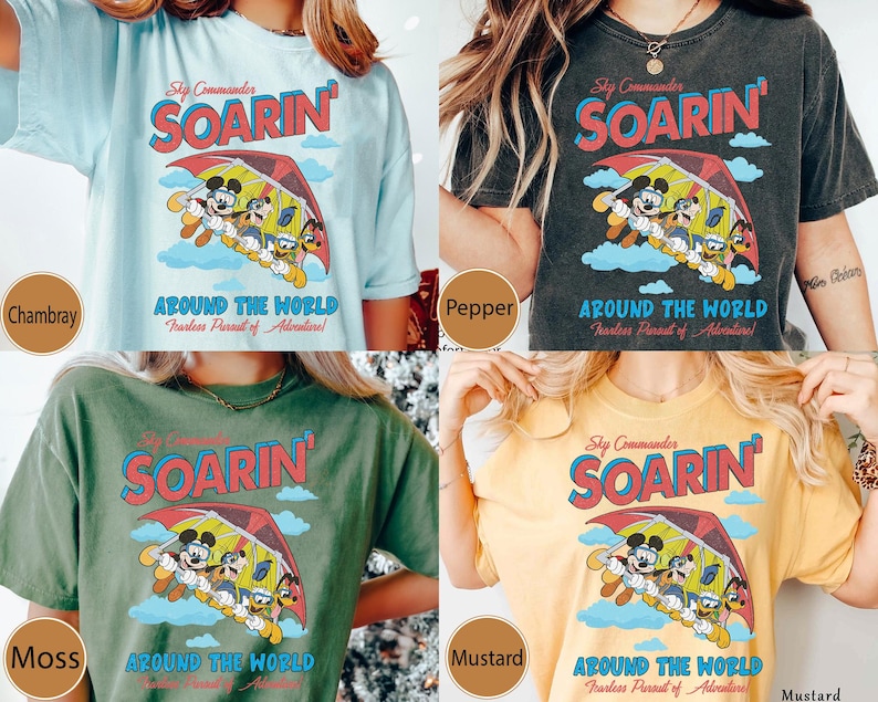 Puede incluir: Cuatro camisetas de diferentes colores con un gr&aacute;fico de estilo vintage de Mickey Mouse y sus amigos volando en un ala delta. El gr&aacute;fico incluye el texto "Sky Commander Soarin' Around the World Fearless Pursuit of Adventure!"