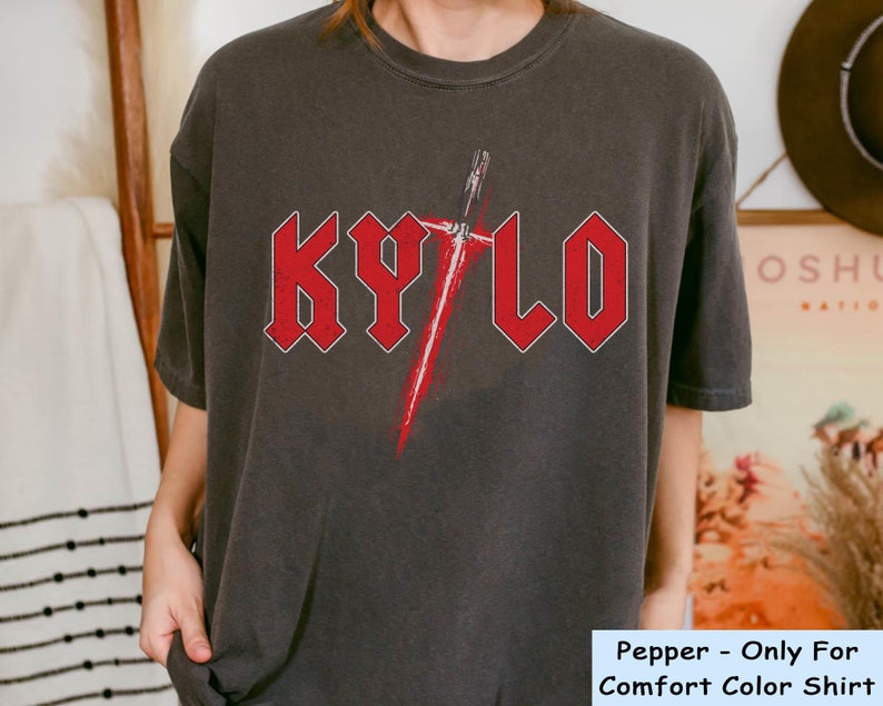 May include: A dark grey t-shirt with a red graphic of a lightsaber and the word "KYLO" in red letters. The shirt is a comfort colour shirt.