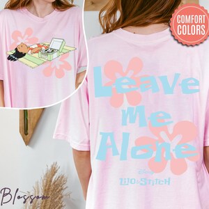 Puede incluir: Camiseta rosa claro con un gr&aacute;fico de un personaje y un tocadiscos, y el texto "Leave Me Alone" con acentos florales. La camiseta es de Lilo & Stitch de Disney.