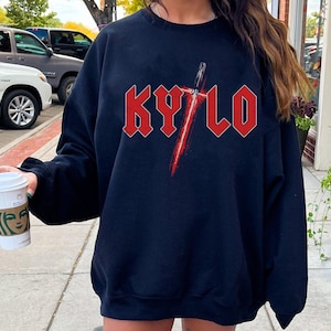 May include: Black sweatshirt with a red graphic of a lightsaber and the word "KYLO" in red block letters.